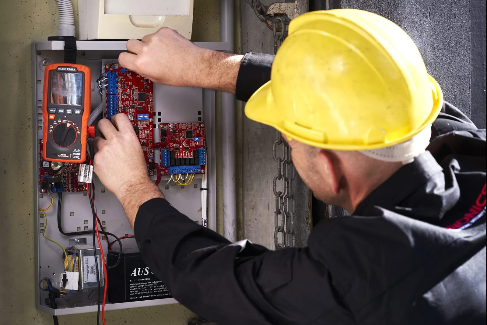 Ktronics technician commissioning an access control board with a multimeter