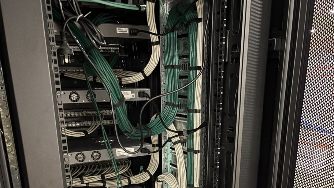 Densely populated data centre cabinet with bundled green and white cabling running into Cisco-class switching gear