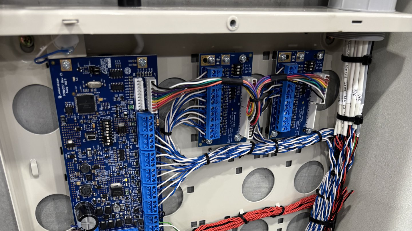 Overhead galvanised cable tray dropping into a Sharkrack comms cabinet inside the warehouse