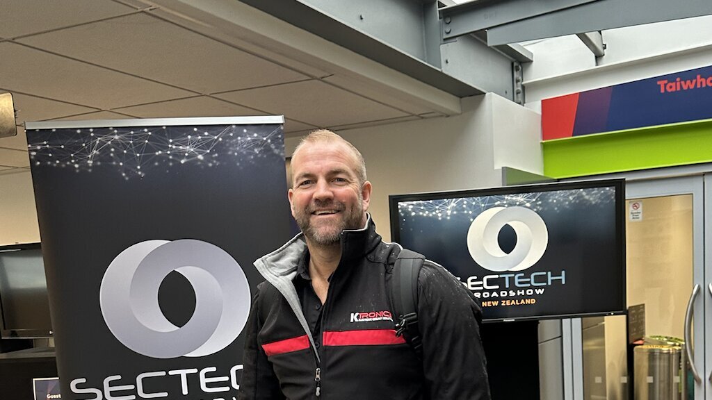 Karl Lamb arriving at the SecTech Roadshow 2026 with kit bag, branded SecTech banner behind